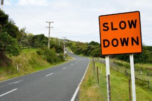 A winding road with an orange sign that says slow down represents cannabis tolerance breaks for medical patients.